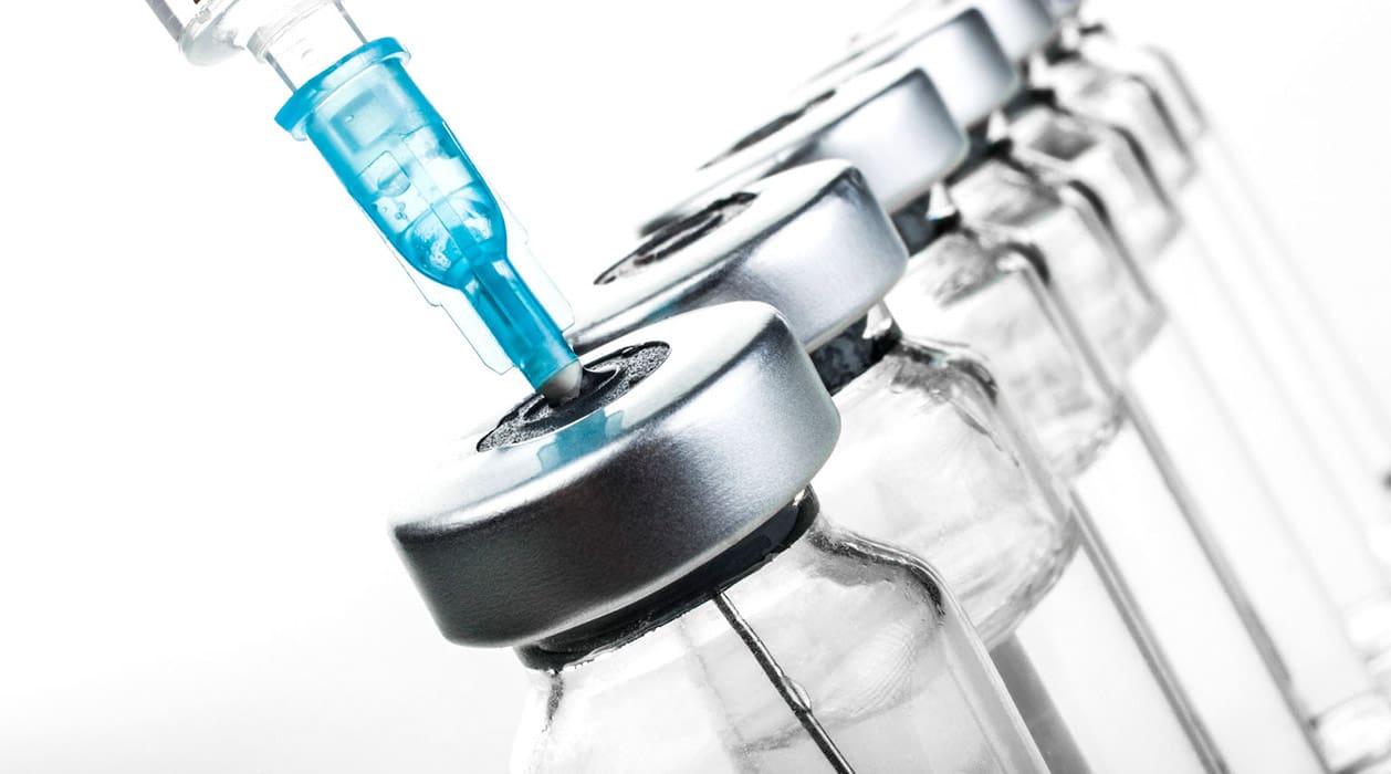 A row of empty glass bottles with one blue liquid in them.